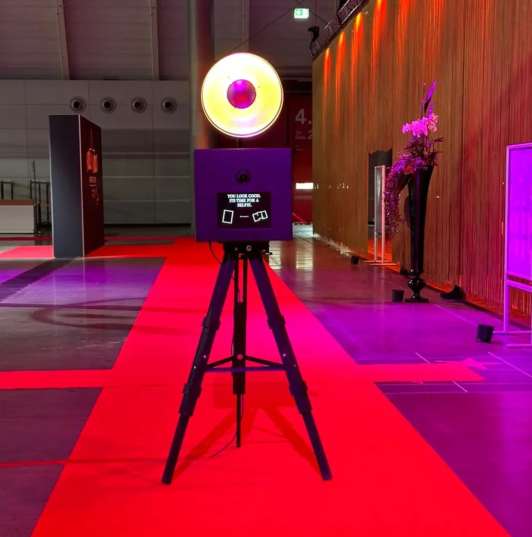 Moderne Fotobox mit Ringblitz steht auf einem roten Teppich in einer stilvoll beleuchteten Eventlocation.